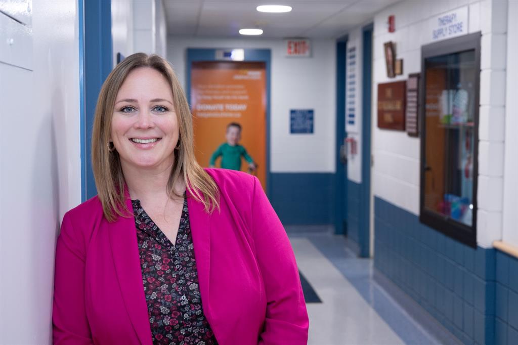 Women in pink blazer stands in hallway